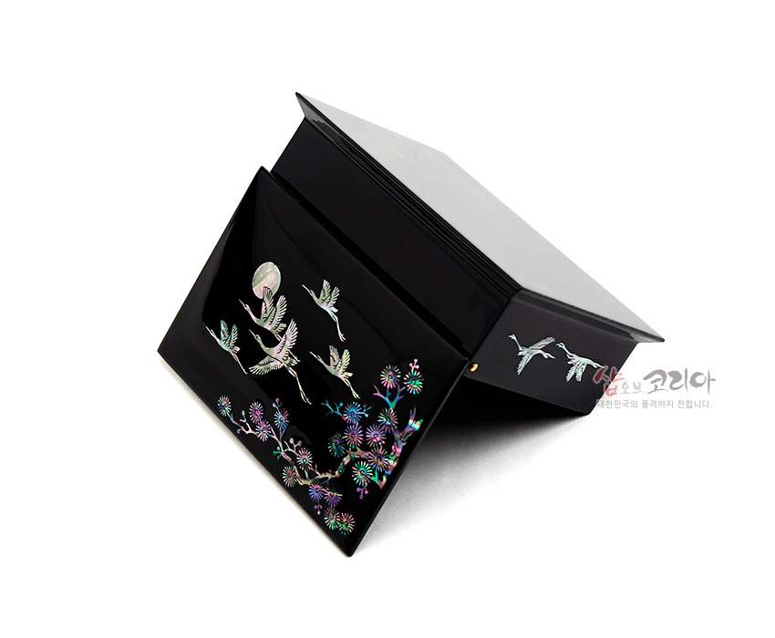[텍스트: 샵오브코리아 대한민국의 품격까지 전합니다] 흑색 옻칠 바탕 위 자개 상감 기법으로 달과 비상하는 학, 소나무와 국화 문양을 화려한 오방색으로 표현한 직사각형 명함함 이미지 설명