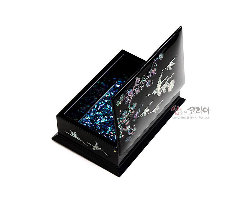 [텍스트: 샵오브코리아 대한민국의 품격까지 전합니다.] 흑색 옻칠 바탕에 자개 상감 기법으로 학과 국화, 소나무 문양을 넣고 내부는 푸른 자개 조각으로 장식한 직사각 명함함 이미지 설명