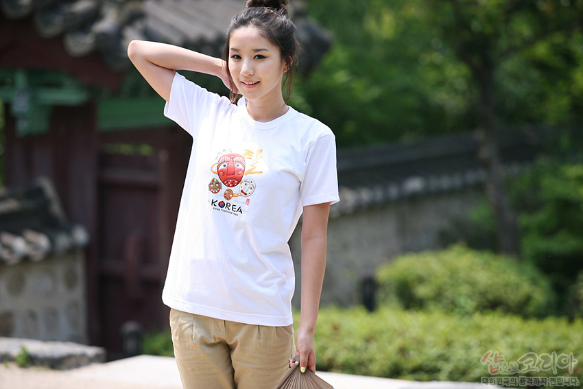 [텍스트: KOREA] 흰색 면 티셔츠에 붉은 하회탈과 다양한 전통 탈 캐릭터를 3D 발포 프린트로 표현한 반소매 디자인 이미지