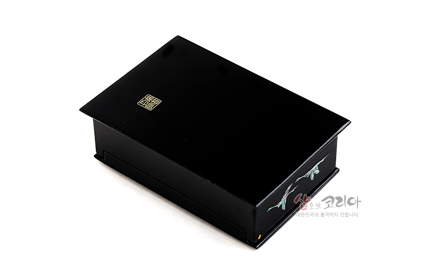 [텍스트: 샵오브코리아, 정다운 한국의 품격까지 전합니다.] 흑색 옻칠 사각 명함함 상단 금색 인장 문양, 측면 자개 상감 학 문양 장식된 디자인