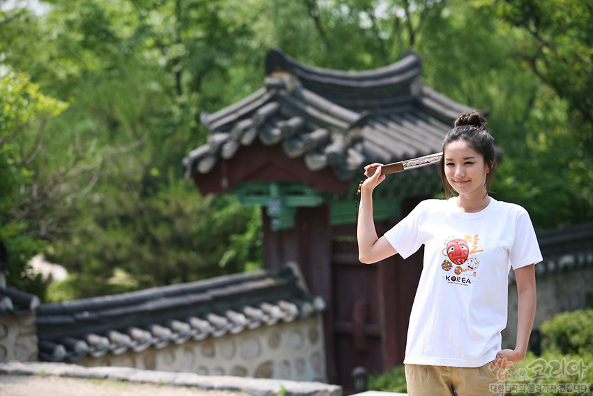 [텍스트: KOREA] 흰색 면 티셔츠 위 하회탈 모티브와 붉은·노랑 색조의 3D 발포 프린트, 한글 캘리그래피 조합의 전통문양 그래픽 연출 이미지