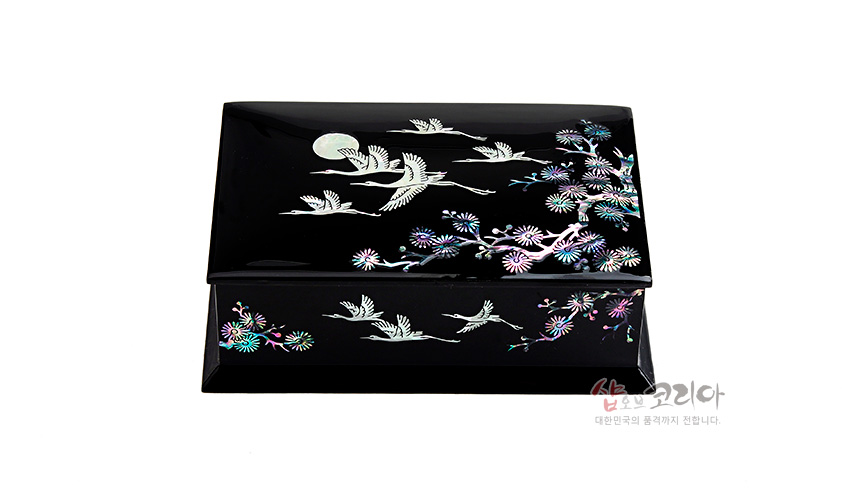 [텍스트: 샵오브코리아 대한민국의 품격까지 전합니다.] 흑색 옻칠 바탕에 자개 상감 기법으로 달과 학, 국화와 소나무 문양을 섬세하게 표현한 직사각 명함함 이미지 설명
