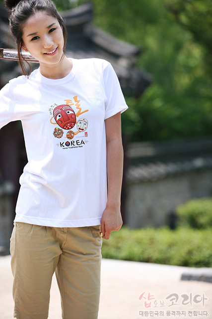 [텍스트: KOREA, shopofKOREA] 흰색 면 티셔츠 위 전통 하회탈과 한글 캘리그래피, 원형 가면 문양을 3D 발포 기법으로 표현한 다채로운 그래픽 디자인