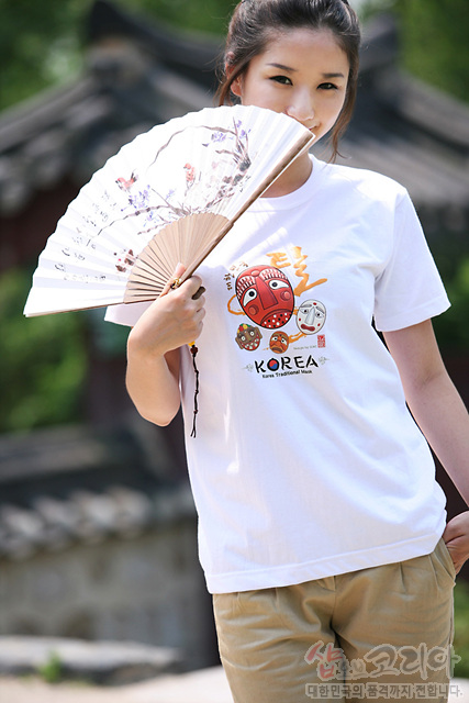 [텍스트: KOREA, Korea Traditional Mask] 흰색 면 티셔츠 위 전통 탈 캐릭터와 한글·영문 조합 3D 발포 프린트, 붉은색·노란색 포인트 색감 강조 디자인