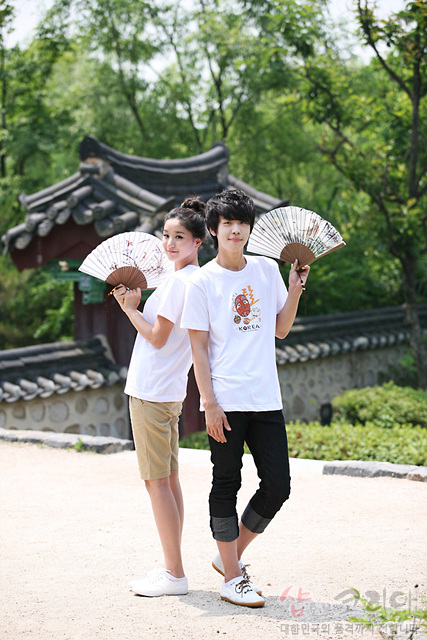 [텍스트: KOREA] 흰색 면 티셔츠에 하회탈 캐릭터와 한글·영문 조합 3D 발포 프린트, 선명한 오렌지·브라운 색채 전통 가면 문양 강조 이미지