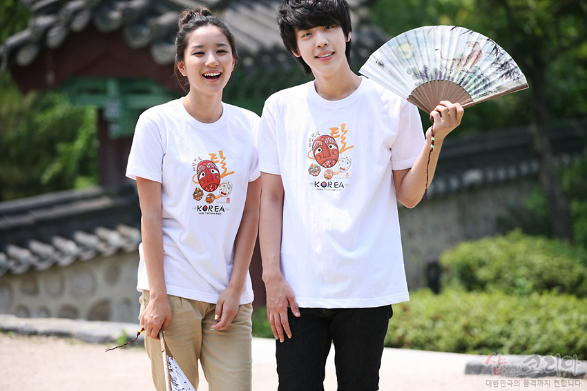 [텍스트: KOREA] 흰색 면 티셔츠 위 전통 탈 캐릭터와 한글 효과음, 원형 배치된 탈 문양이 3D 발포 프린트로 표현된 일러스트 디자인