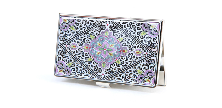 흑백 대비 금속 바탕 위에 분홍·연두 색상의 당초무늬를 에나멜 기법으로 채운 대칭형 장식 명함집 디자인