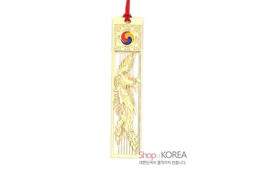 [텍스트: Shop of KOREA / 대한민국의 품격까지 전합니다.] 금장 금속 소재에 정교한 봉황 투각문양과 상단 태극 문양, 붉은색 전통 매듭 끈 장식의 조화로운 책갈피 이미지 설명