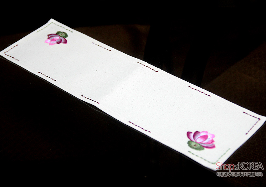 [텍스트: Shop of KOREA 대한민국의 공예품까지 전합니다] 광목 소재 아이보리 직사각 식탁보, 양 끝 분홍 연꽃 자수와 가장자리 포인트 색실 스티치 장식 디자인