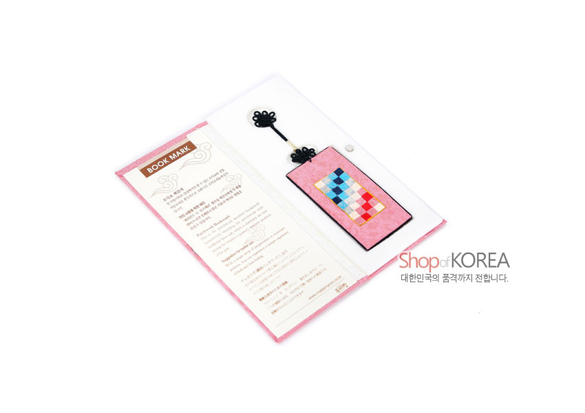 [텍스트: BOOK MARK, Shop of KOREA 대한민국의 품격까지 전합니다.] 분홍색 비단 바탕 위 다채로운 사각 조각보 패치워크와 검은 전통 매듭 장식이 어우러진 직사각형 책갈피 이미지 설명