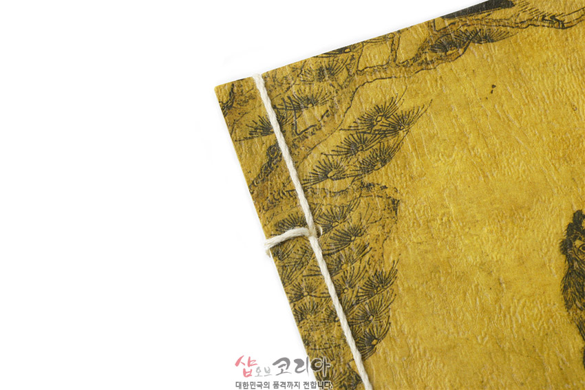 [텍스트: 샵오브코리안 대한민국의 품격까지 전합니다] 황색 한지 표지 위 먹선으로 그린 소나무와 호랑이 민화 문양, 흰 실로 장정한 전통 제본 노트 디테일 이미지