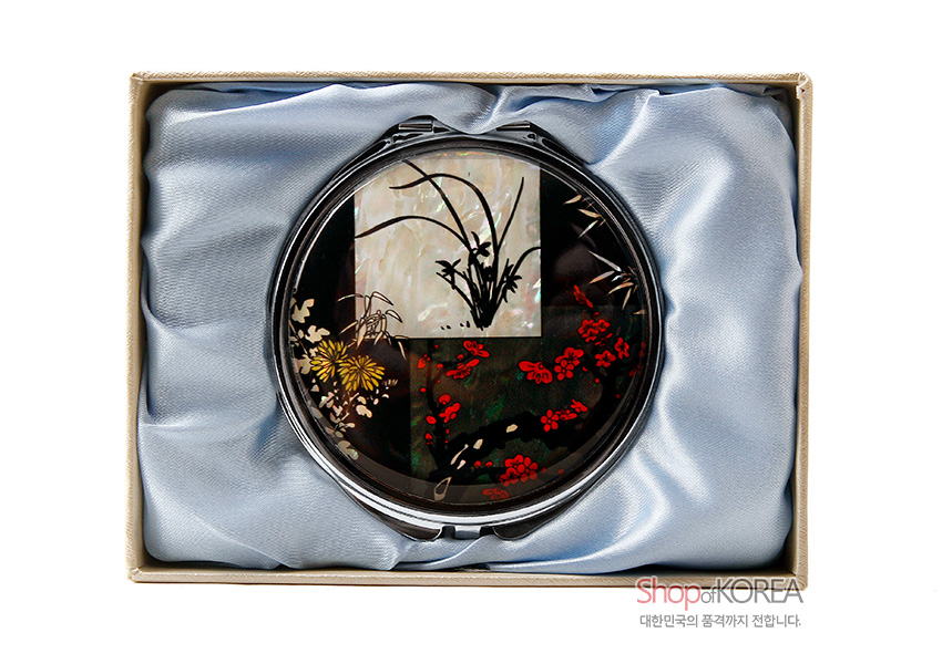 [텍스트: ShopofKOREA 대한민국의 품격까지 전합니다.] 자개 상감 기법의 원형 금속 손거울, 옻칠 바탕 위 사군자 문양과 붉은 매화, 국화, 난초가 대비되는 디자인