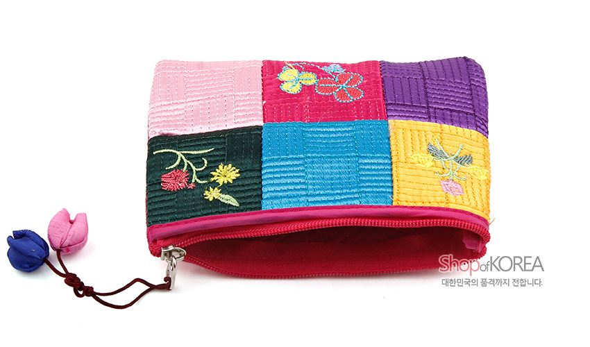 [텍스트: Shop of KOREA 대한민국의 품격까지 전합니다.] 분홍을 중심으로 노랑·파랑·보라 비단 색동 조각을 누비 기법으로 이어 만든 동전지갑, 꽃 자수와 복주머니 모양 매듭 장식 특징
