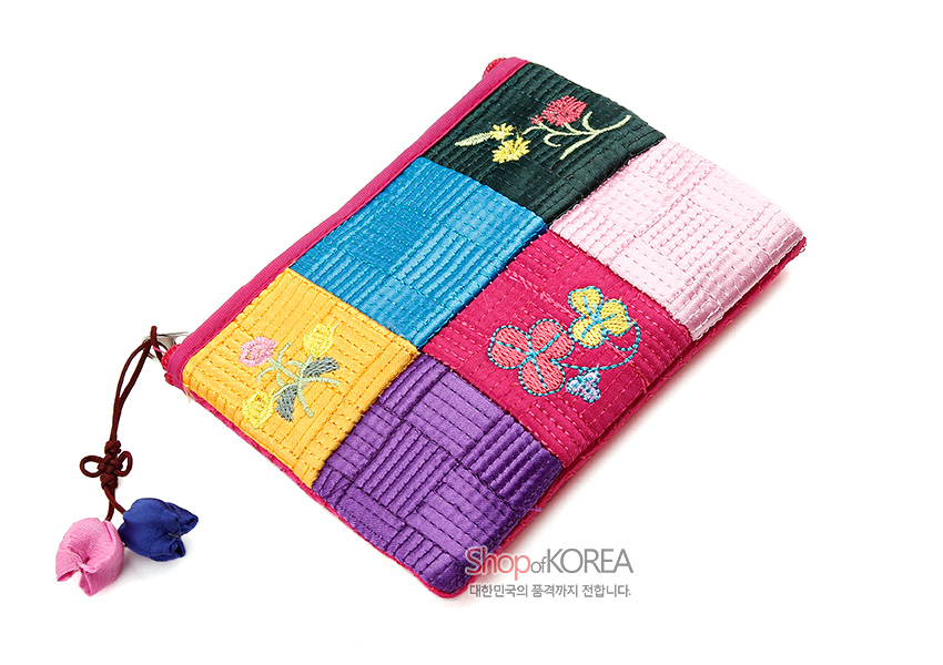 [텍스트: Shop of KOREA 대한민국의 품격까지 전합니다.] 색동 비단 누비 기법으로 구성된 분홍 동전지갑, 격자 누빔과 꽃 자수 문양, 양쪽 끝 복주머니 모양 매듭 장식 특징