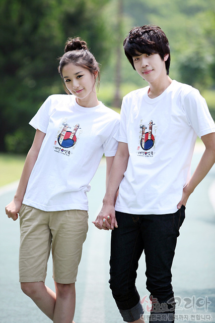 [텍스트: 대한민국] 흰색 면 티셔츠 위 장승 형상과 붉은·푸른 태극 문양을 3D 발포 프린트로 표현한 전통 그래픽 디자인