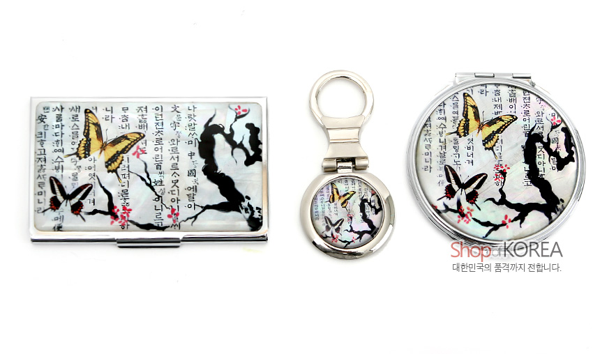 [텍스트: 나랏말ᄊᆞ미 듕귁에 달아 문자와로 서르 사맛디 아니할ᄊᆞ든, 이런 전차로 인하여] 금속 바탕 위 자개 느낌 광택에 매화나비와 한글 훈민정음 서체를 흑백·노랑·분홍 색조로 장식한 명함집·열쇠고리·손거울 세트 이미지 설명