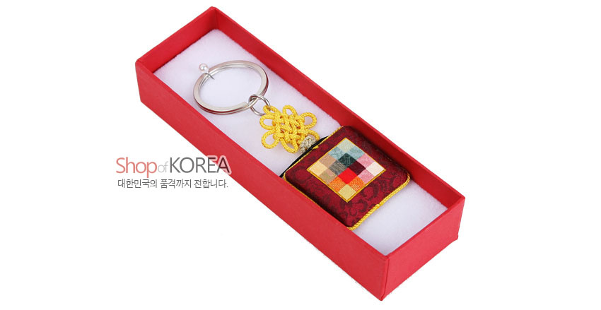 [텍스트: Shop of KOREA / 대한민국의 품격까지 전합니다.] 자주색 비단 바탕에 다채로운 색 실크 조각보 누비 장식과 노란 전통 매듭, 금속 고리가 조합된 사각 거울 열쇠고리 구성