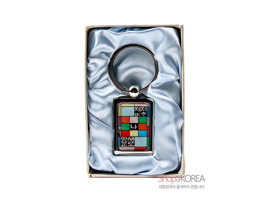 [텍스트: 제자부, 나, 문, 안, 셰, 례] 금속 테두리에 자개 상감된 사각 펜던트, 오방색 조각보 패턴과 훈민정음 글자 배열이 조화된 열쇠고리 이미지 설명