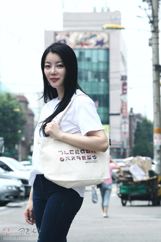 [텍스트: HANGUL KOREAN ALPHABET] 흰색 면 티셔츠와 에코백에 다채로운 색상의 한글 자음 입체발포 프린트가 가로로 배열된 캐주얼한 거리 패션 연출 모습