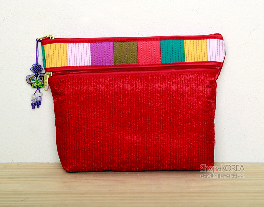 [텍스트: Shop of KOREA 대한민국의 품격까지 전합니다] 붉은 비단 누비 바탕에 분홍·노랑·초록 등 색동 누비 줄무늬 장식과 나비 매듭 장식이 달린 지퍼 파우치 지갑 모습