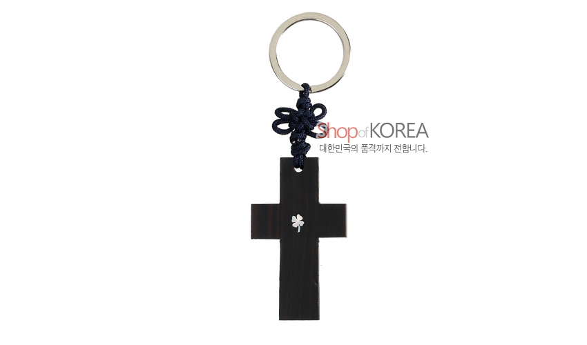 [텍스트: Shop of KOREA 대한민국의 품격까지 전합니다.] 흑단 십자가 본체에 작은 클로버 자개 상감, 남색 전통 매듭과 금속 링이 조화된 열쇠고리 디자인