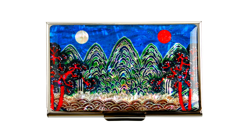 자개 상감 기법으로 표현한 청색 하늘 아래 오봉과 해·달, 붉은 소나무와 물결무늬가 어우러진 금속 테두리 명함집 이미지 묘사