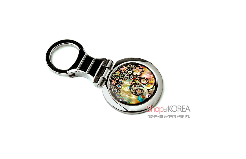 [텍스트: ShopofKOREA 대한민국의 품격까지 전합니다.] 금속 테두리에 자개 상감 기법으로 공작과 꽃 문양을 넣은 다채로운 색감의 원형 열쇠고리 디자인