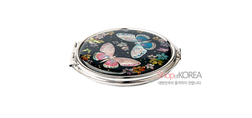 [텍스트: shop of KOREA 대한민국의 품격까지 전합니다.] 검은 바탕 위에 자개 상감 기법으로 표현된 나비와 꽃 문양이 화려하게 배치된 원형 금속 손거울 디자인