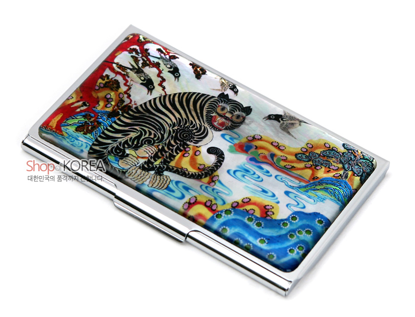 [텍스트: Shop of KOREA / 대한민국의 품격까지 전합니다.] 자개 바탕 위에 옻칠로 표현한 까치호랑이와 산수문, 청·홍·황의 강렬한 대비와 금속 테두리가 조화를 이룬 명함집 이미지 설명