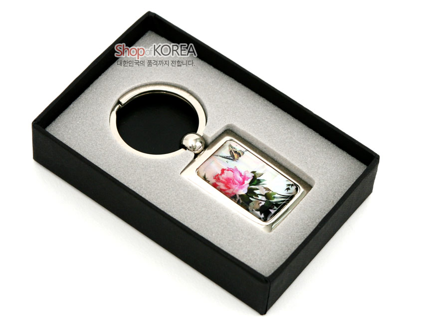[텍스트: Shop of KOREA, 대한민국의 품격까지 전합니다.] 금속 사각 프레임 속 채색 자개 판에 담홍색 꽃과 나비 문양을 상감한 열쇠고리 이미지