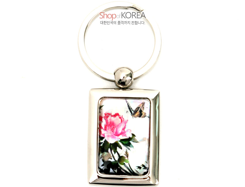 [텍스트: Shop of KOREA 대한민국의 품격까지 전합니다.] 금속 사각 프레임 안에 채색 자개를 상감하여 연분홍 꽃과 나비 문양을 담은 열쇠고리 디자인