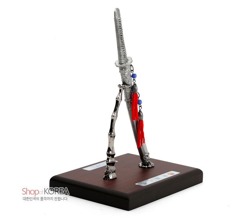 [텍스트: Shop of KOREA 대한민국의 품격까지 전합니다.] 금속 재질 한국도와 대나무 형상 스탠드, 목제 받침 위 적·청색 구슬과 붉은 매듭이 장식된 전통 도검 모형 장식품