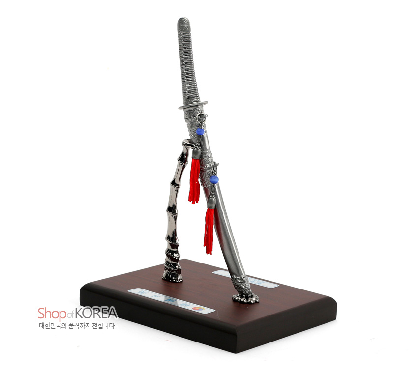 [텍스트: Shop of KOREA 대한민국의 품격까지 전합니다.] 금속 주석 재질 한국도 모형과 대나무 형상 스탠드, 적색 술매듭과 청색 구슬 장식이 올려진 목제 받침 조형품