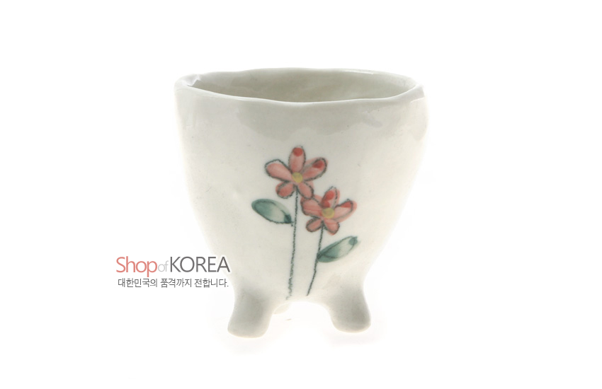 [텍스트: Shop of KOREA / 대한민국의 품격까지 전합니다.] 백색 도자기 재질, 삼각 다리 굽과 물결형 입구, 수채화 느낌 분홍 야생화 문양이 그려진 소주잔 형태 이미지설명