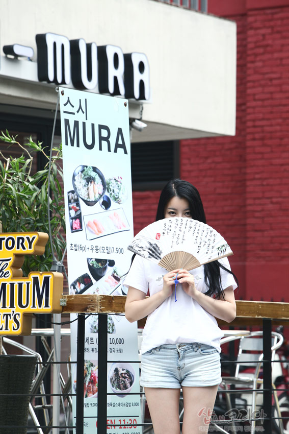 [텍스트: 스시 MURA, 초밥(6p)+우동(모밀) 7,500, 세트 10,000] 흰색 티셔츠와 청반바지를 입은 인물이 서예 문양과 풍경이 그려진 전통 접선 들고 있는 장면