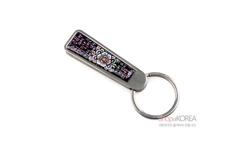 [텍스트: Shop of KOREA 대한민국의 품격까지 전합니다.] 금속 틀에 자개 상감 기법으로 시조 한글과 단청 꽃문양을 넣은 직사각형 열쇠고리 디자인