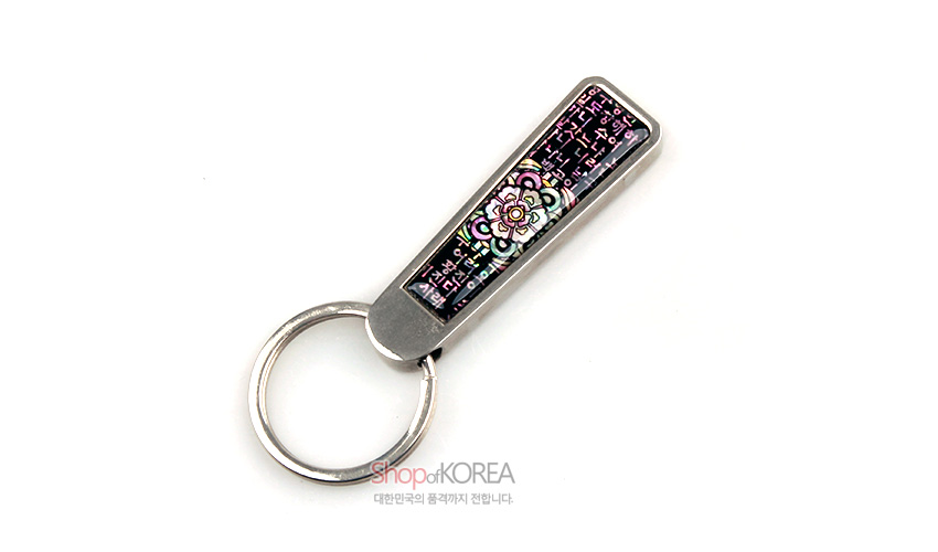 [텍스트: 밝은 달이 온 세상을 두루 비춘다] 금속 테두리에 자개 상감 기법으로 시조 글귀와 단청 꽃문양을 넣은 열쇠고리 디자인
