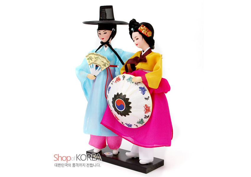 [텍스트: Shop of KOREA / 대한민국의 품격까지 전합니다.] 비단 한복을 입은 선비와 기생 인형, 색동 고름과 자수 노리개, 태극·나비 문양 부채와 장식이 어우러진 전통 공예 인형 세트 표현