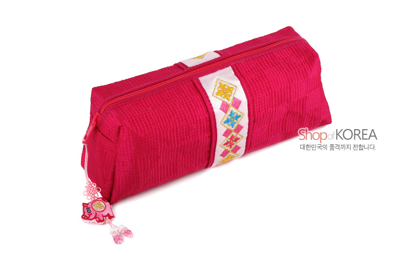 [텍스트: Shop of KOREA 대한민국의 품격까지 전합니다.] 선명한 적색 누비 비단 재질, 흰색 띠 위 기하학 색동 자수 문양과 복돼지 매듭 장식이 특징인 필통 형태의 파우치