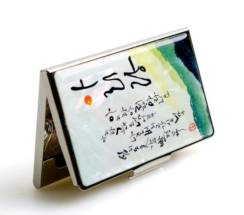 [텍스트: (아리랑 가사 서예)] 자개 바탕 위 수묵담채풍 녹청색 그라데이션과 아리랑 가사 서예가 조화된 금속 명함집 디자인