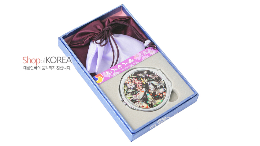[텍스트: Shop of KOREA 대한민국의 품격까지 전합니다.] 파란 포장 상자 속 금속 테두리 자개 나비·꽃문양 원형 손거울과 자주색 비단 복주머니 구성 이미지