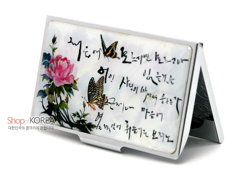 [텍스트: Shop of KOREA 대한민국의 품격까지 전합니다.] 자개 바탕 위 분홍 목단과 나비, 흑색 한글 서예 문양이 어우러진 금속 테두리 명함집 디자인