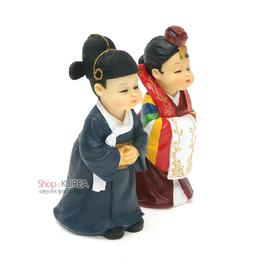 [텍스트: Shop of KOREA 대한민국의 품격까지 전합니다.] 레진 소재 전통혼례 신랑신부 인형, 남색 도포와 흰 동정, 오방색 색동 소매와 금색 자수 문양 활옷, 족두리 장식 표현