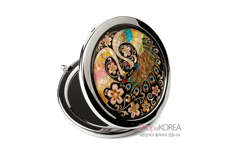 [텍스트: ShopofKOREA 대한민국의 품격까지 전합니다.] 금속 테두리에 천연 자개 상감 기법으로 공작과 꽃문양을 다채로운 색감으로 표현한 원형 원터치 손거울 디자인