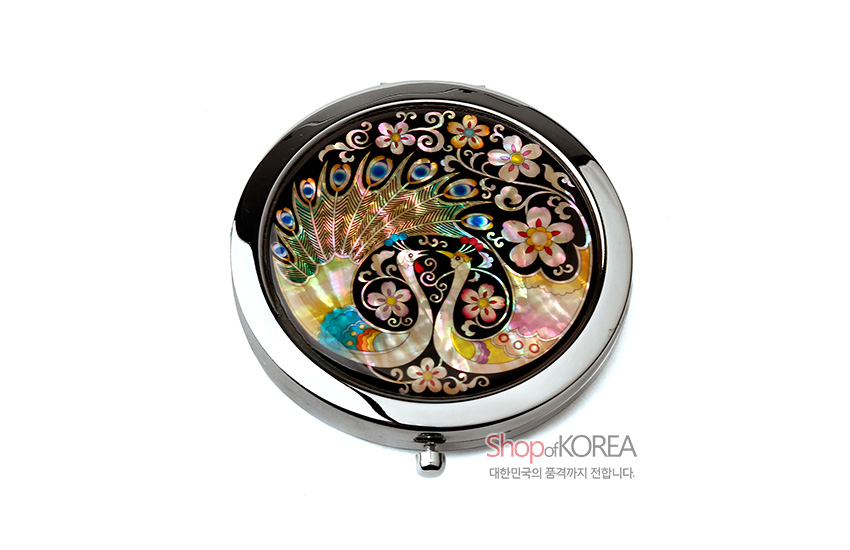 [텍스트: ShopofKOREA 대한민국의 품격까지 전합니다.] 자개 상감 기법으로 공작 한 쌍과 공작 깃털, 벚꽃 문양을 섬세하게 표현한 원형 금속 테두리 원터치 손거울 디자인