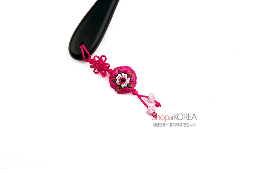[텍스트: Shop of KOREA 대한민국의 품격까지 전합니다.] 검은색 손잡이 끝에 연분홍 비단 매듭과 꽃 자수 장식, 분홍 매듭 술이 연결된 손거울 디테일 이미지
