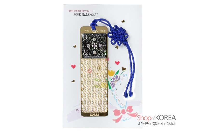 [텍스트: Best wishes for you…, BOOK MARK-CARD, 자개책갈피, 당초문, KOREA, Shop of KOREA, 대한민국 품격까지 전합니다.] 금속 바탕 위 자개 상감으로 흑색 바탕 꽃문양과 금색 당초무늬를 넣고 청색 전통 매듭 끈을 단 책갈피 이미지 설명