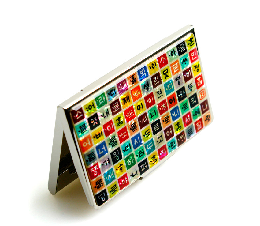 [텍스트: 훈민정음 한글 자모 배열] 금속 테두리 위 자개 바탕에 다채로운 색상의 정사각형 칸을 촘촘히 배열한 명함집 디자인