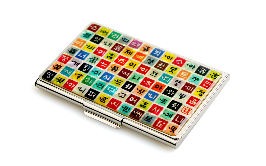 [텍스트: 스언라니어간나디문내디랄자던번별빈이럴아주념골모낀불녀론줄하이룡별나출도제니이버성하아법롭버결것네션워전드늘어이름명니돌모뇨전교야인여원서성롬은모니펄창리벤럄훈민정음] 금속 테두리 위 다채로운 색상의 정사각형 칸에 한글 자모를 배열한 자개 장식 명함집 이미지 설명