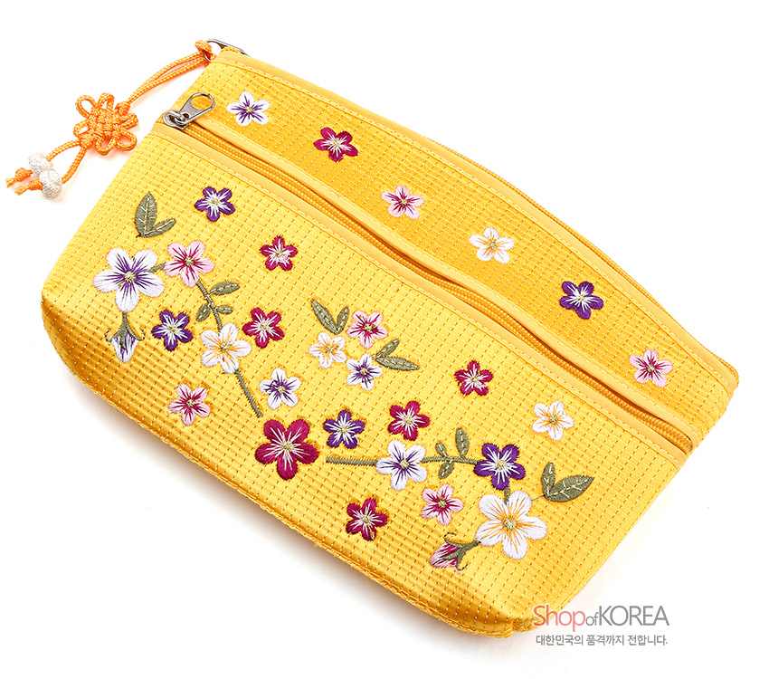 [텍스트: Shop of KOREA 대한민국의 품격까지 전합니다.] 노란 누비 직조 원단 위 다채로운 배꽃 자수와 잎사귀 문양, 매듭 장식 지퍼 손잡이가 어우러진 파우치 디자인